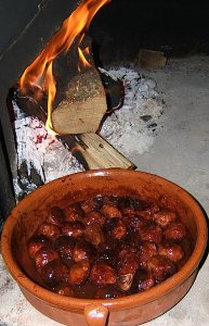 Albondigas (meatballs) in terracotta pan next to a wood fire