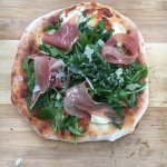 Cooked pizza with Pizza with Prosciutto and Arugula and Shaved Parmagian Cheese