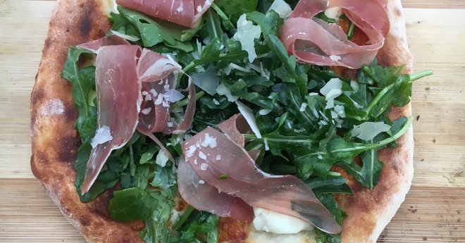 Cooked pizza with Pizza with Prosciutto and Arugula and Shaved Parmagian Cheese