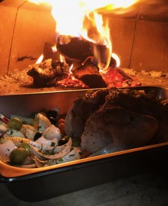 Roasting chicken and vegetables next to the fire in the pizza oven chamber