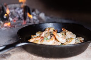 Shrimp cooking in a cast iron pan in a wood fired oven