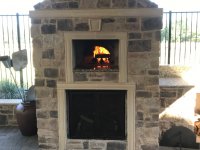 Stone enclosed Artigiano brick pizza oven with fire burning