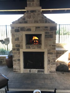 Stone enclosed Artigiano brick pizza oven with fire burning