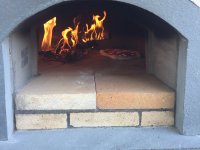 Front of Casa90 pizza oven with wood fire and pizza inside