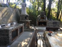 Grey stone faced outdoor kitchen with pizza oven - fireplace - prep area - picnic table