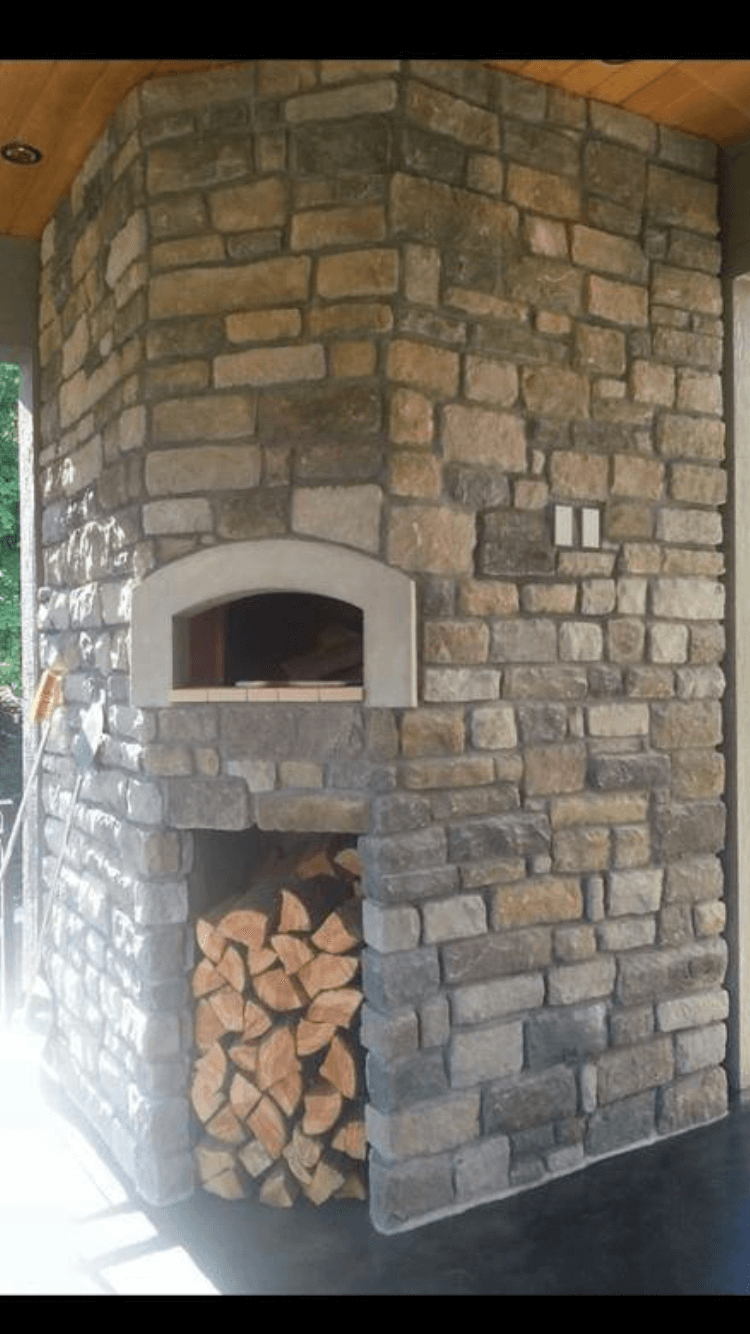 Triangle stone pizza oven enclosure and wood storage area