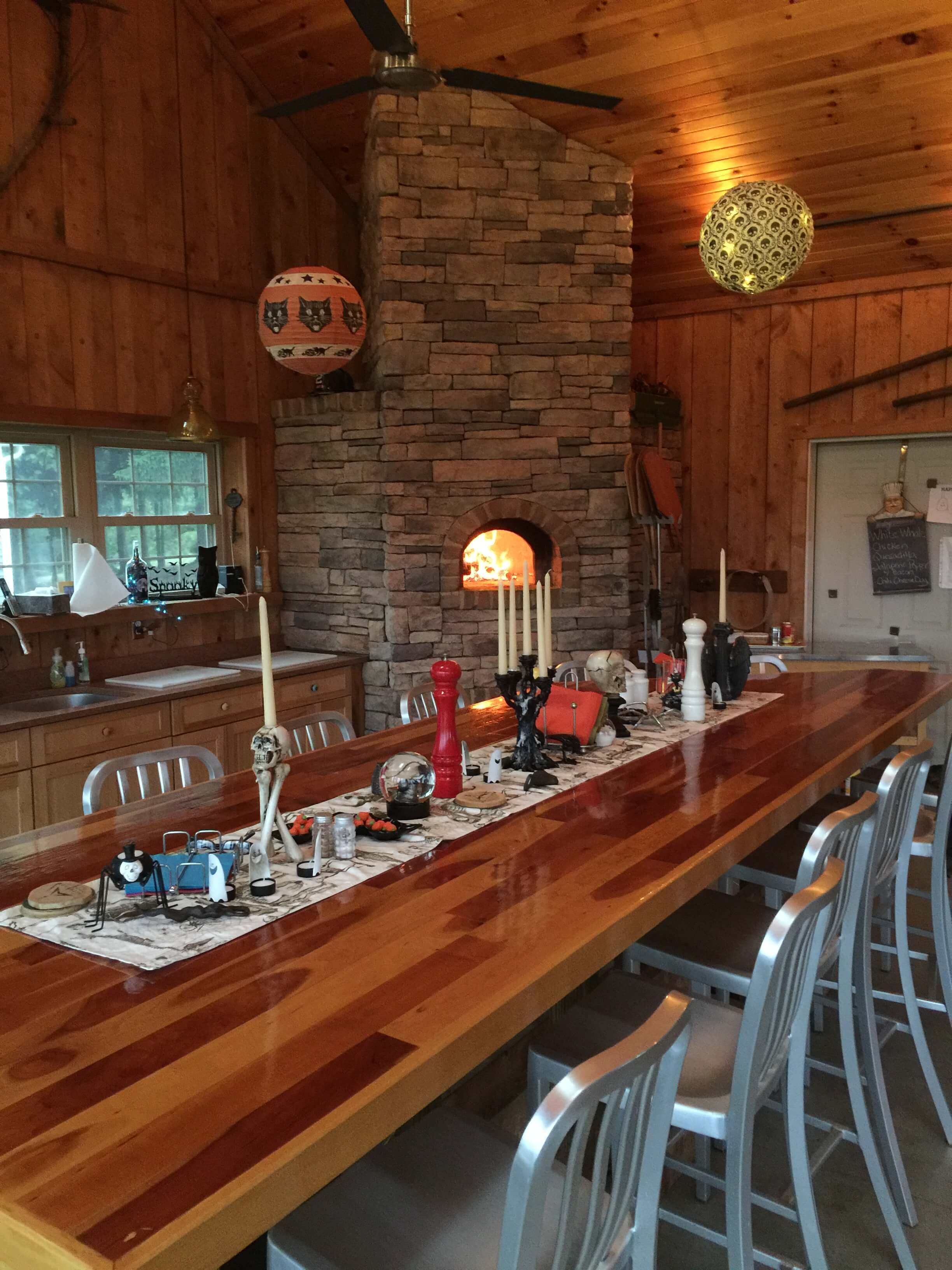 Indoor wood burning pizza oven in a floor to ceiling stone enclosure - Long wooden table set for Halloween