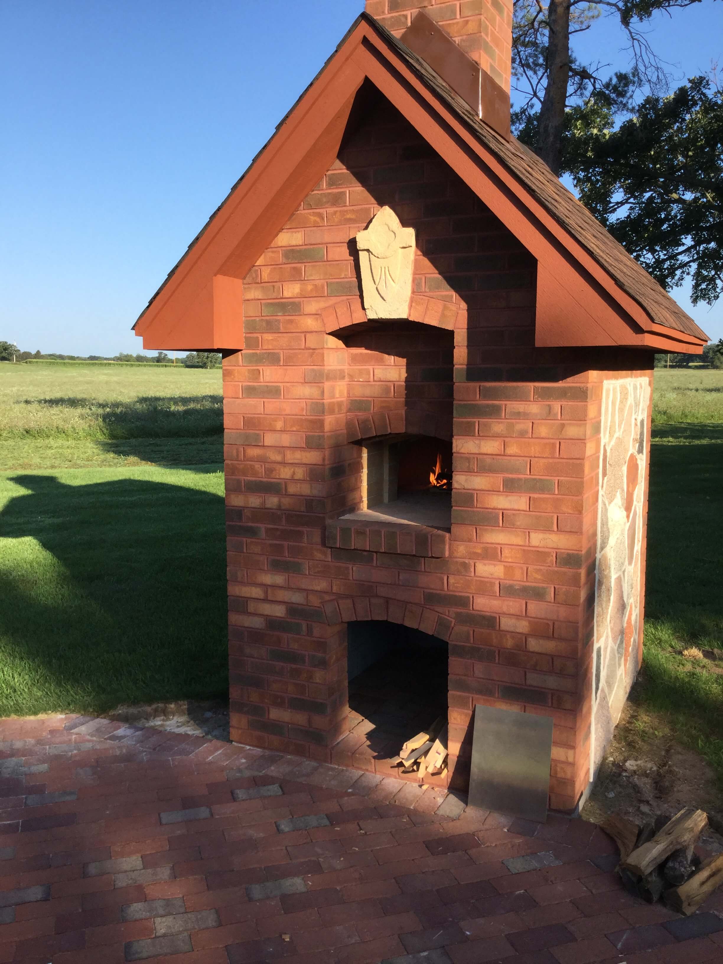 front view of brick faced pizza oven enclosure with river tock accents on the side