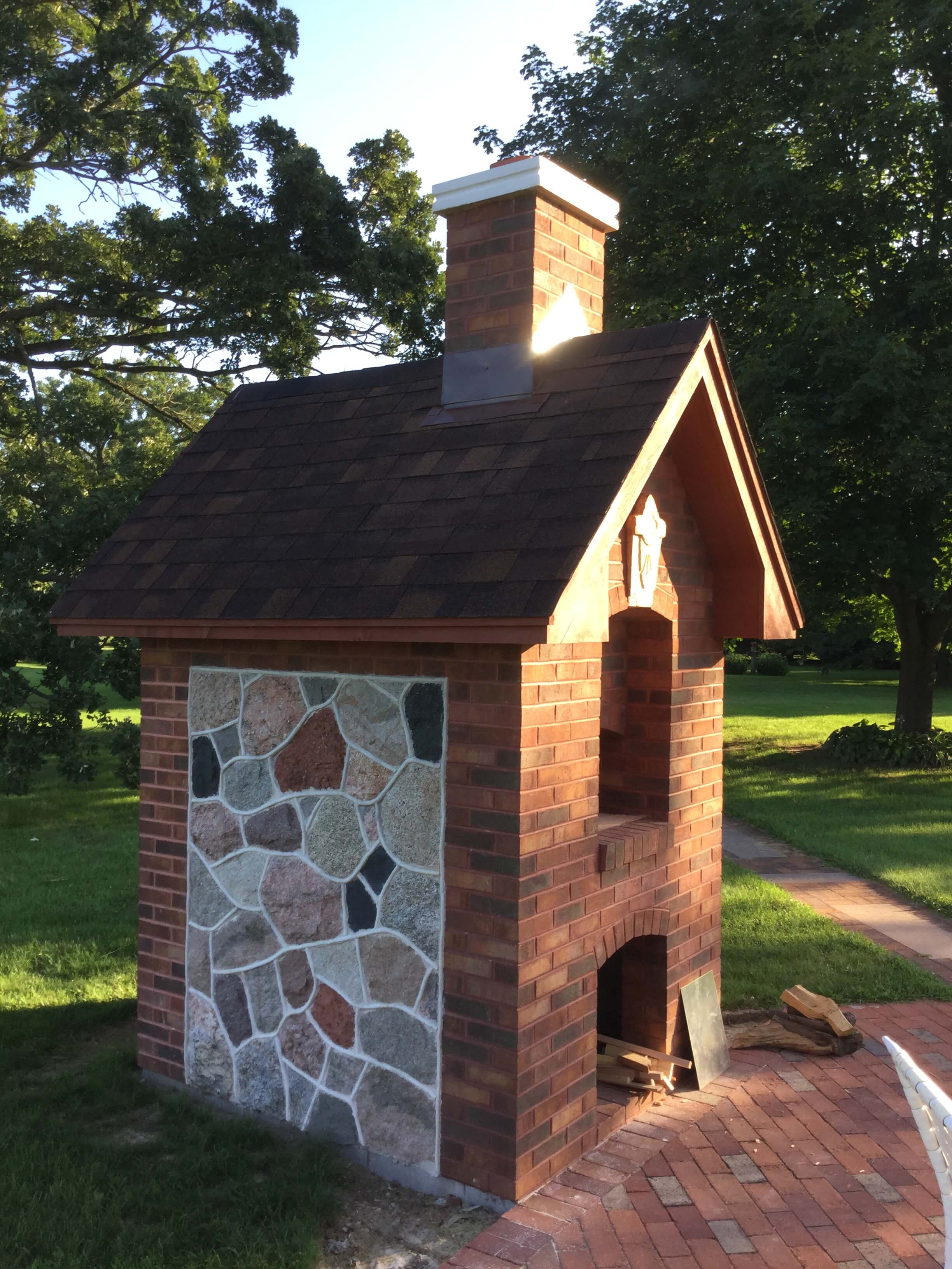 Side view of Pizza Oven and wood storage area with river rock and brick enclosure -red brick patio