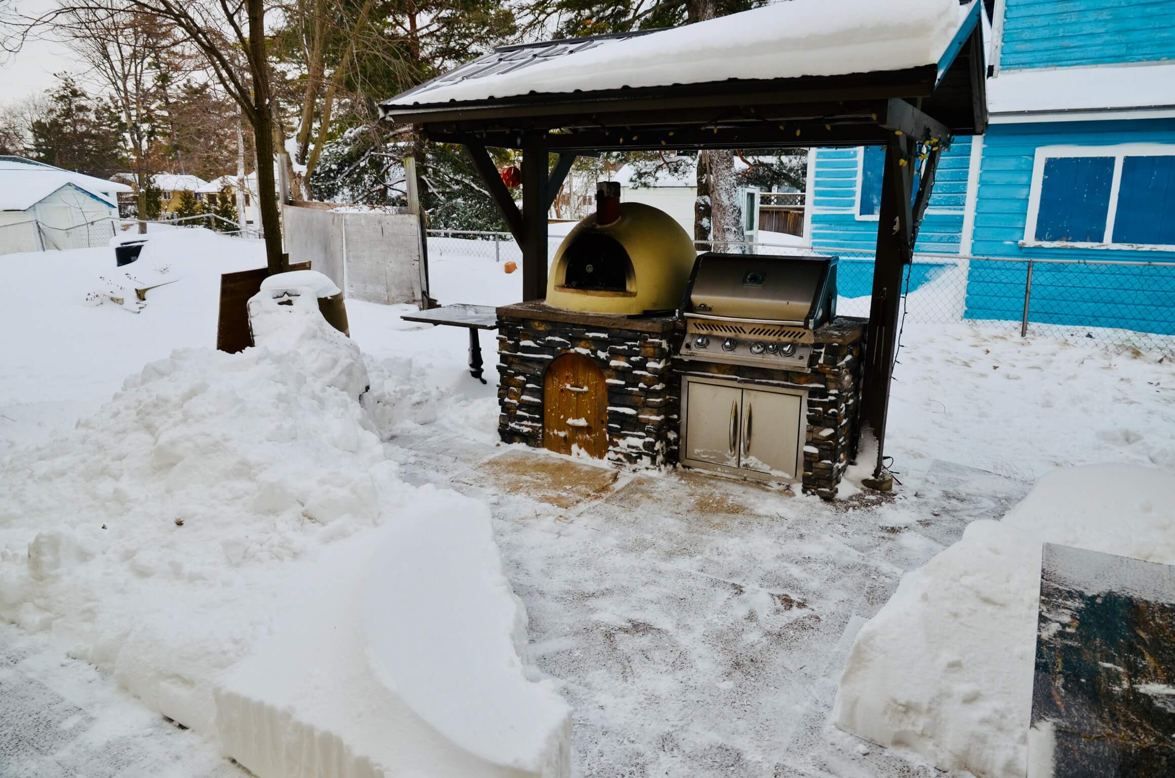 2 feet of snow around a partially scraped patio in front of a covered Primavera 70 and BBQ grill