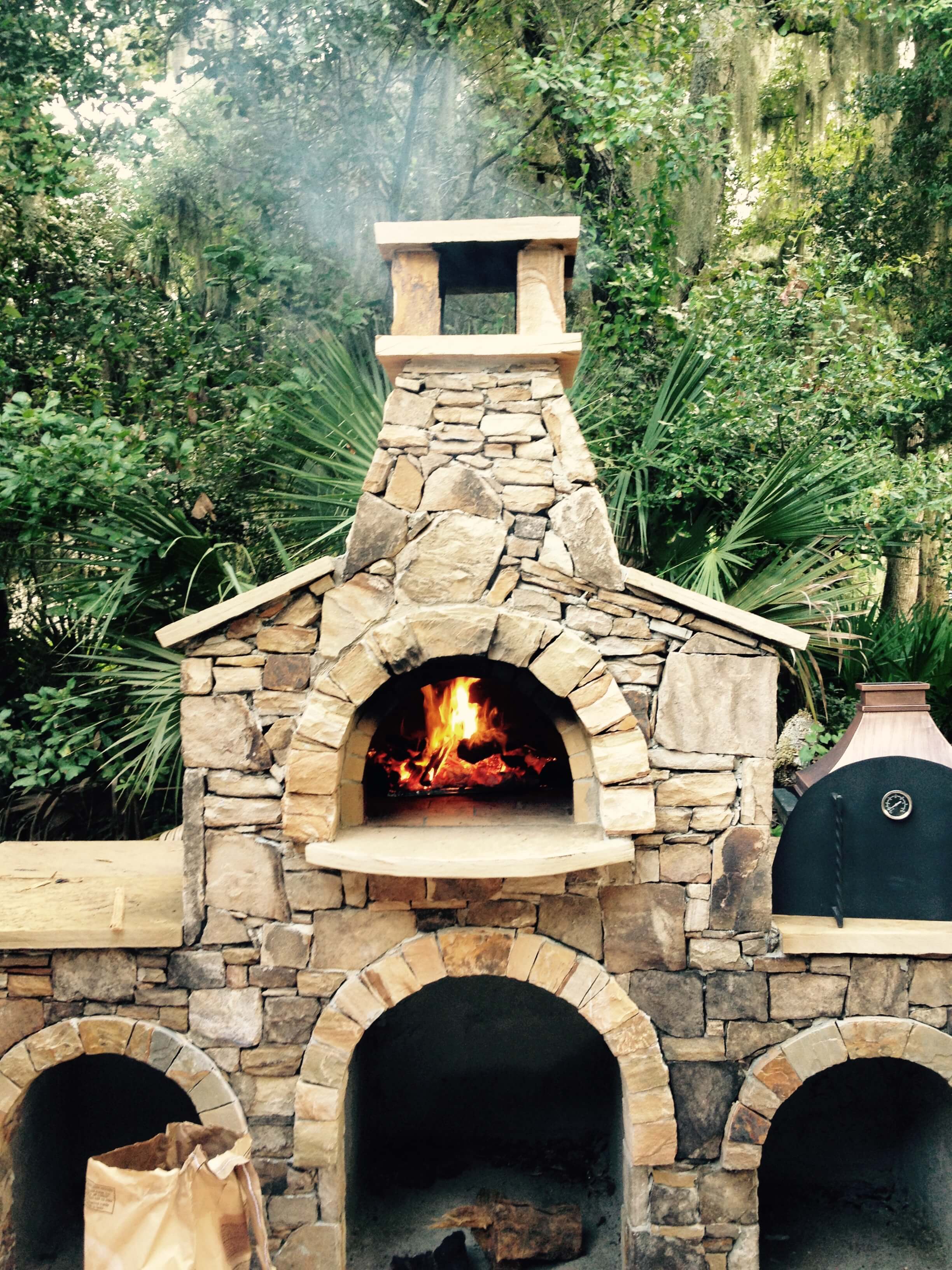 Rock enclosure with multiple arches for pizza oven with burning wood