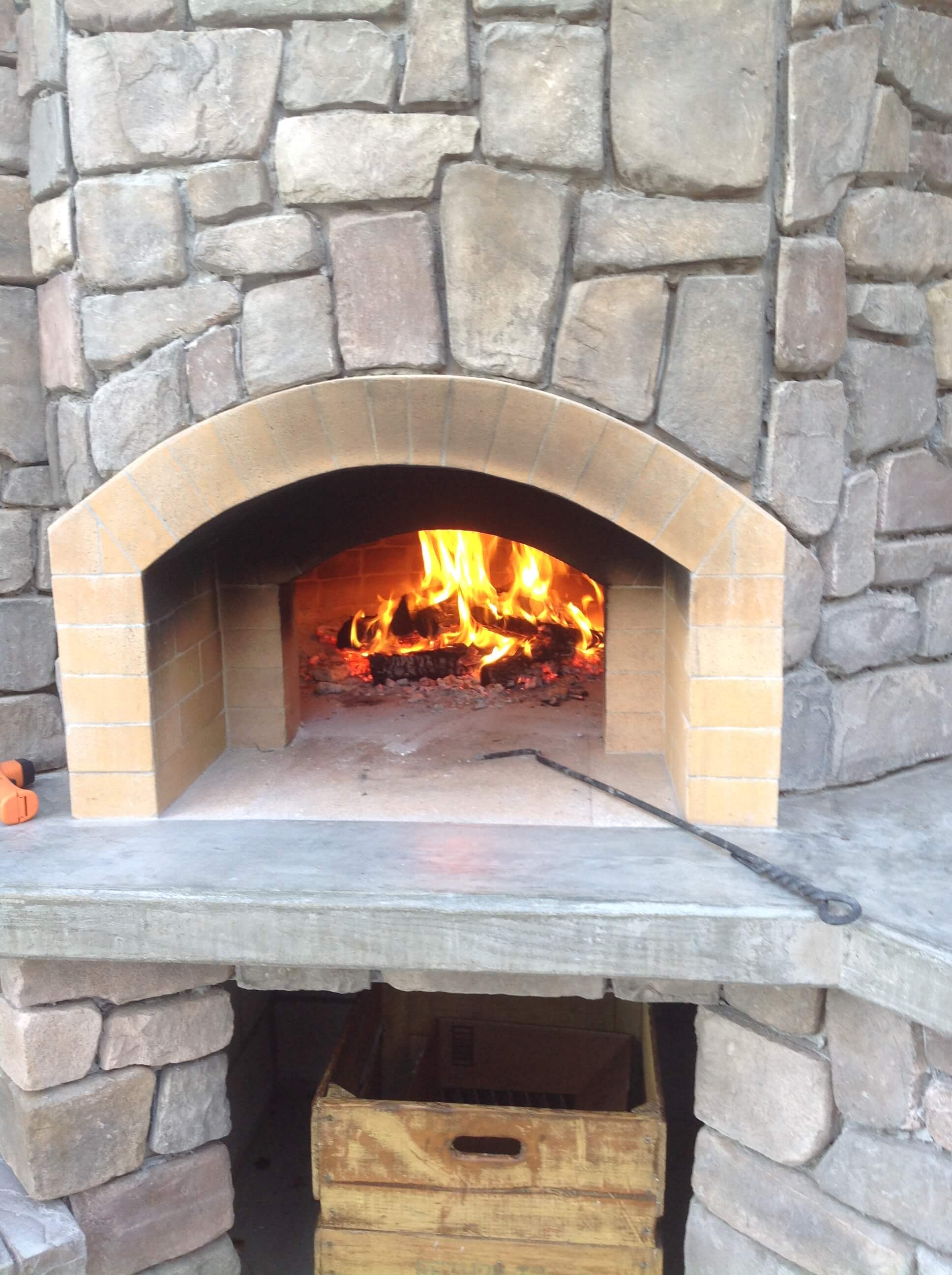Close up of Pompeii Pizza Oven hearth with a burning fire and metal poker