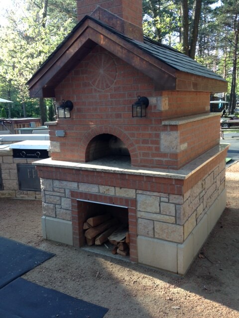 Pizza oven and wood storage enclosure of red brick, granite, and cement blocks