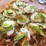 Pizza topped with pancetta-shrimp-vegetables-lettuce-lime_crema-lime_slices-avacado