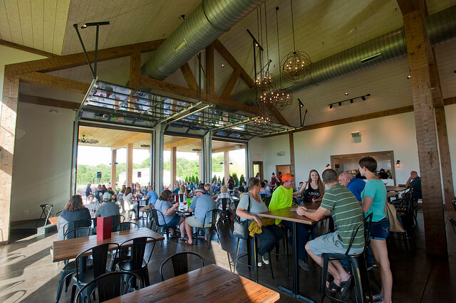 Many people sitting at tables in tsating room at Sharrott Winery