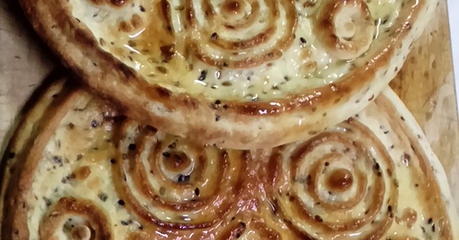 2 baked Eid Bread rounds coated in Olive Oil with Circle Pattern on top