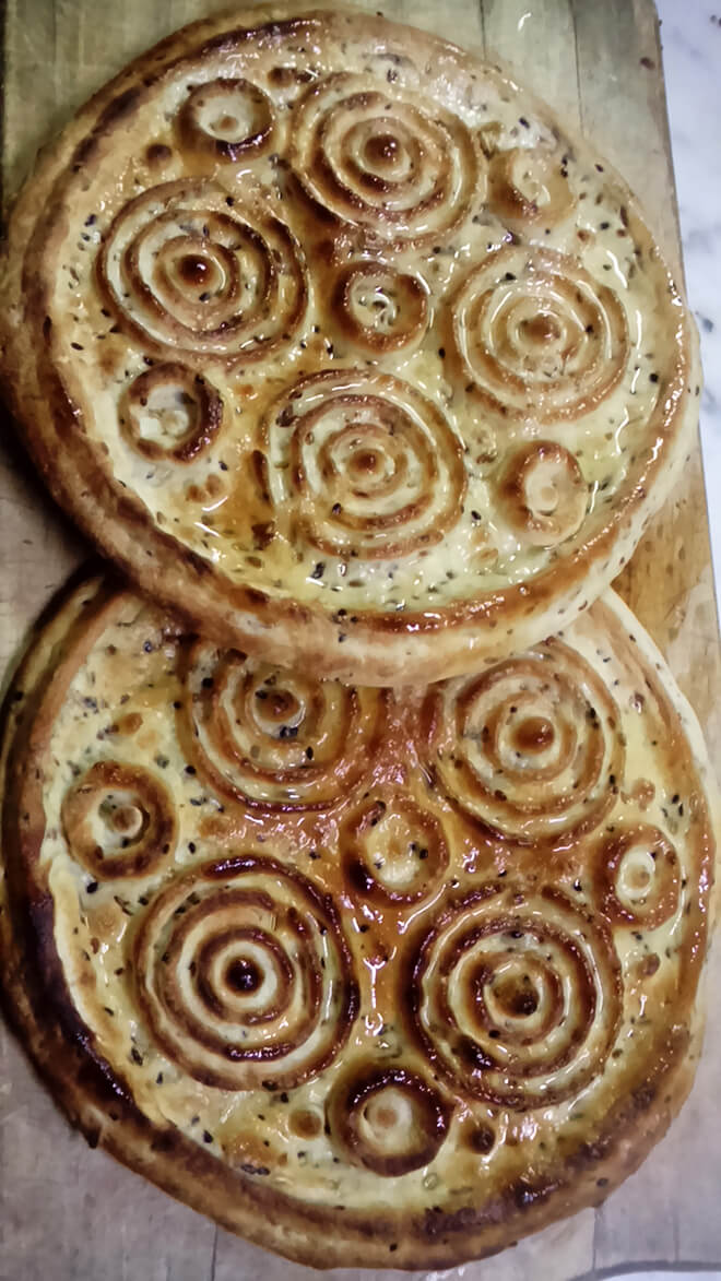 2 baked Eid Bread rounds coated in Olive Oil with Circle Pattern on top