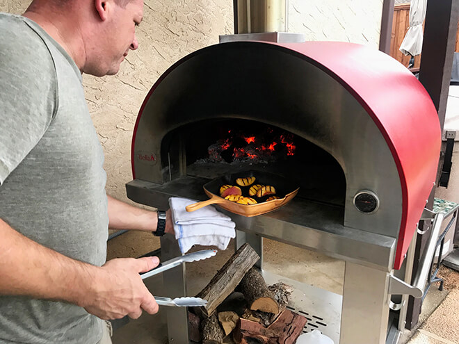 man removing grilled peaches from Bella Grande 32 oven