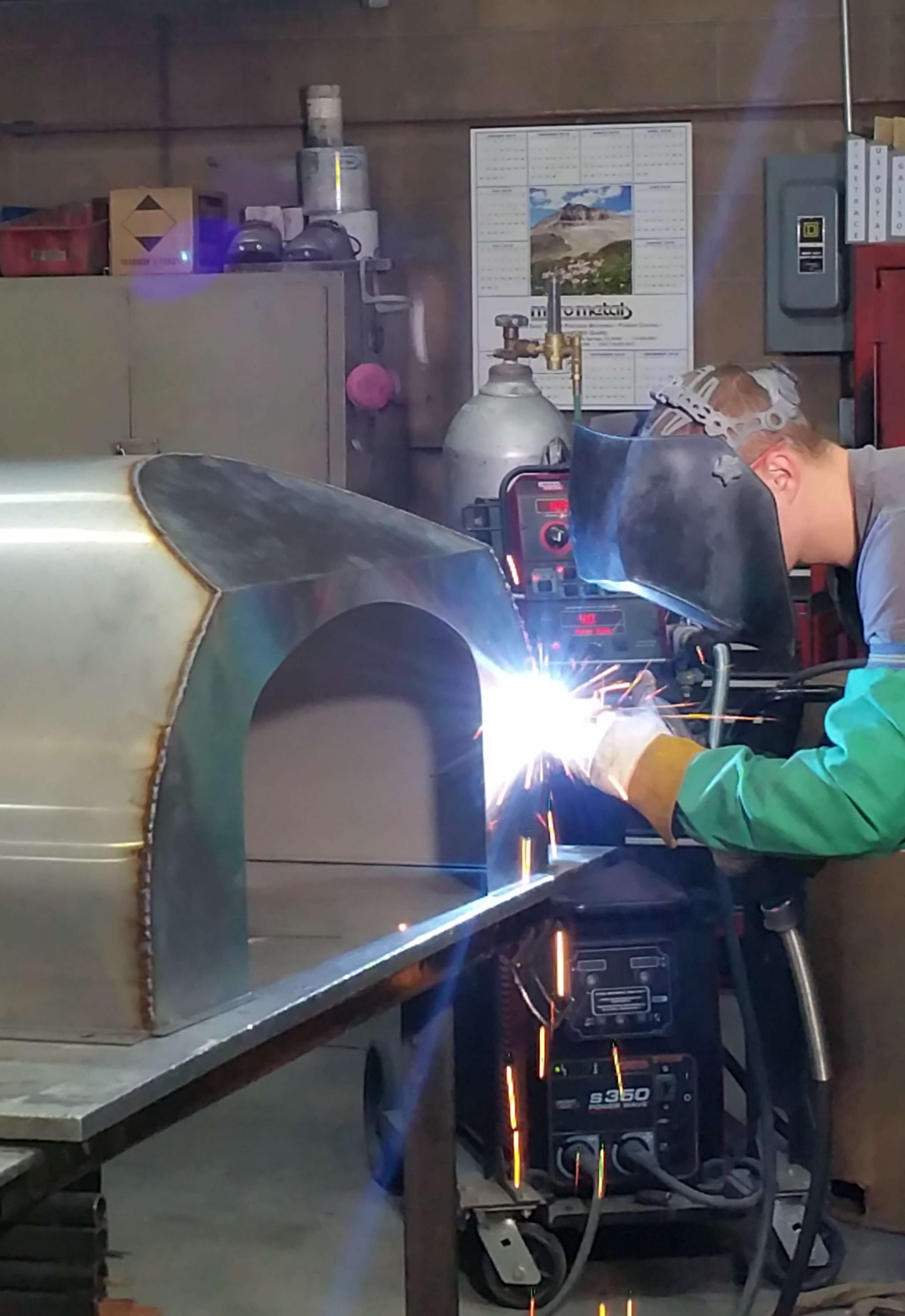 man welding Bell Pizza Oven