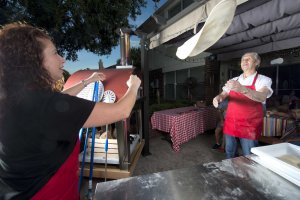 2 people tossing pizza