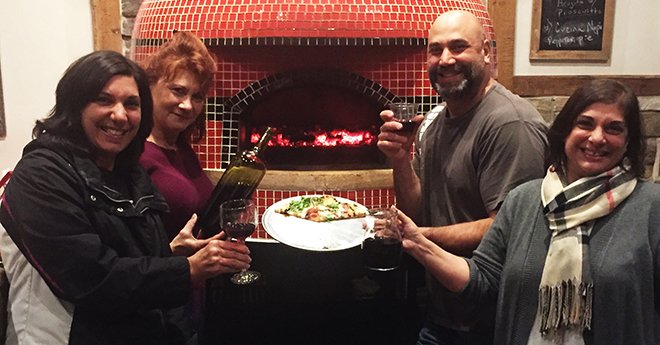 3 women-1 man in front of pizza oven