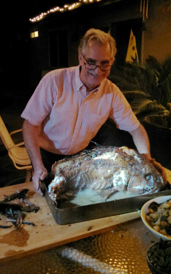 Man in pink shirt with large cooked fish