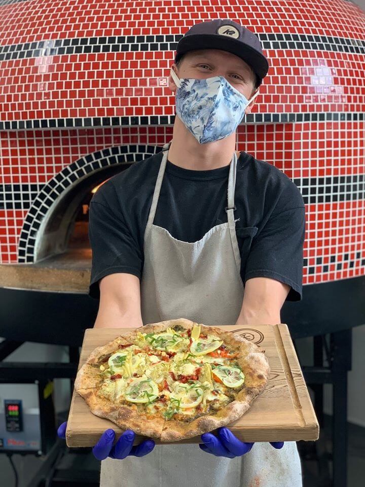 Man in mask presenting pizza