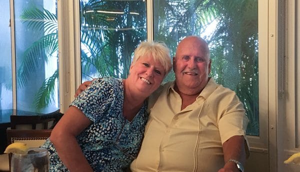 man and woman sitting in front of palms