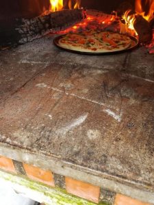 Pizza on pan in wood fire oven