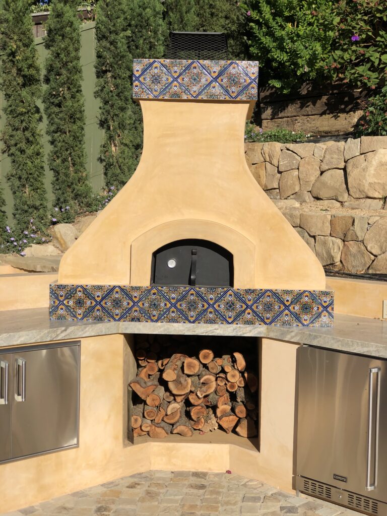 Yellow stucco pizza oven with tall chimney