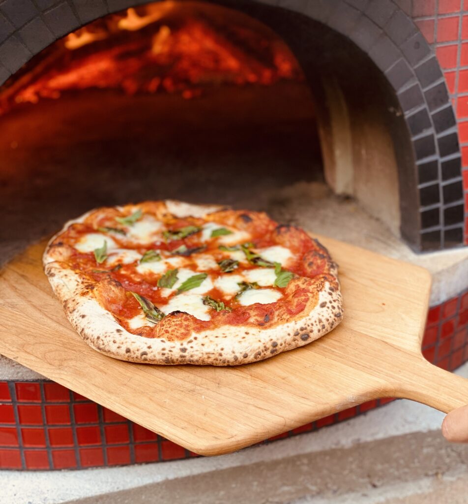 Margherita Pizza on wooden peel coals in pizza ocven