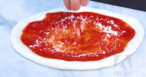 Adding-cheese-to-pizza-dough-and-sauce